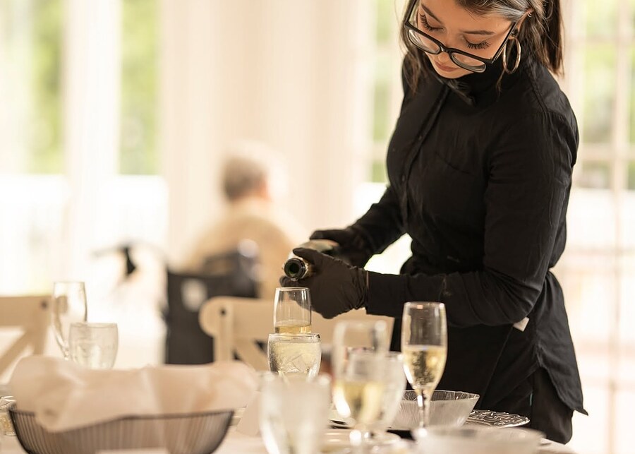 Server pouring champagne at a set reception table