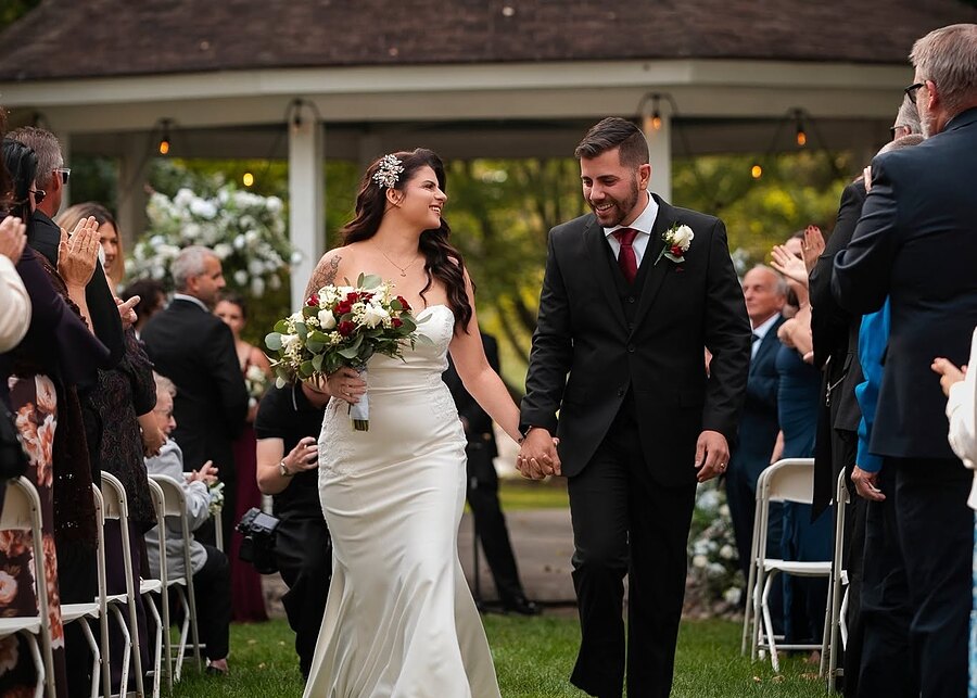 A couple walks back up the aisle at the gazebo as guests applaud
